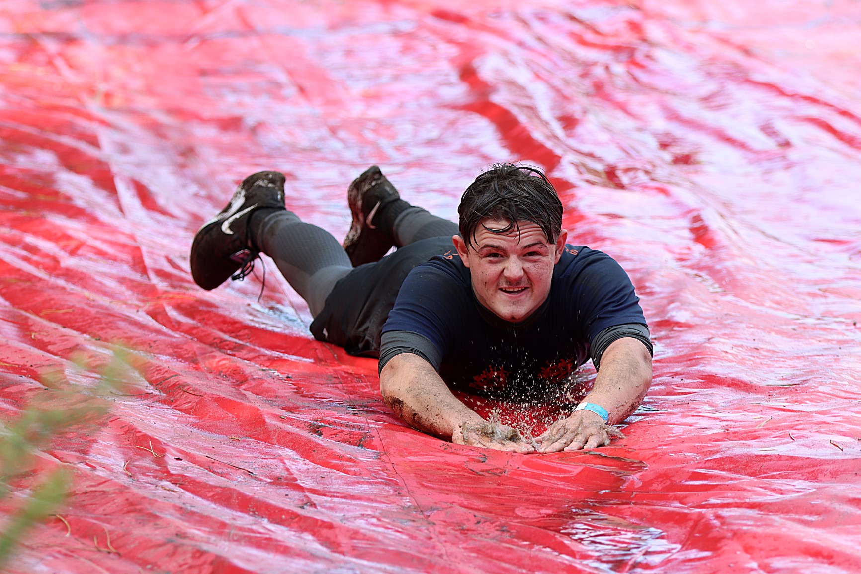 A man slides on his belly on a red canvas